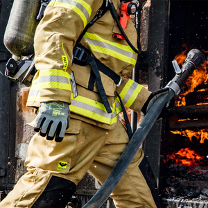 firefighter wearing FireArmor® SR-X® 8180 holding a water hose walking into fire