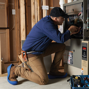 HVAC tech working on furnace with yules on