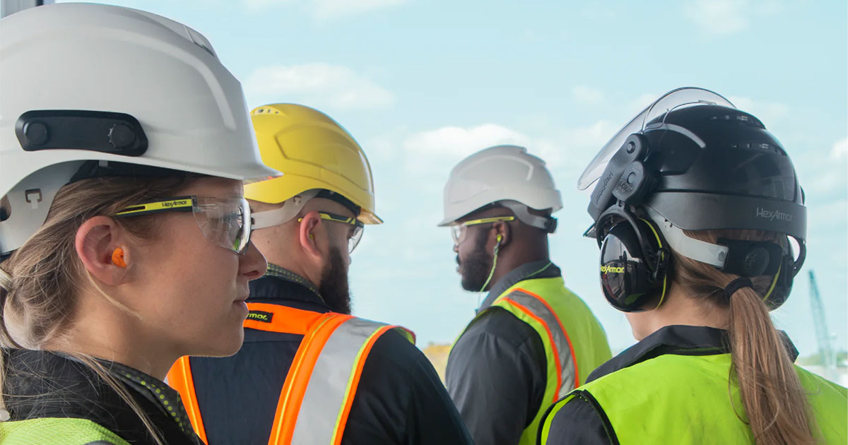 Four construction workers wearing hearing protection and hard hats.