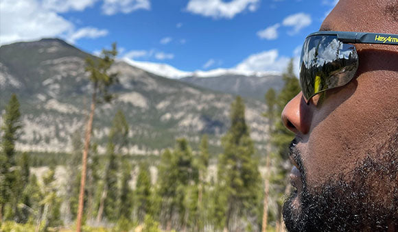 Man wearing safety glasses looking out at a wooded landscape.
