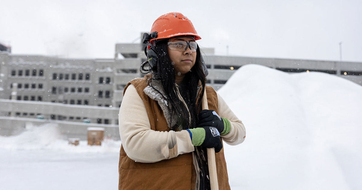 Construction worker standing in front of a snow pile wearing a pair of Helix cold weather 2073 safety gloves.