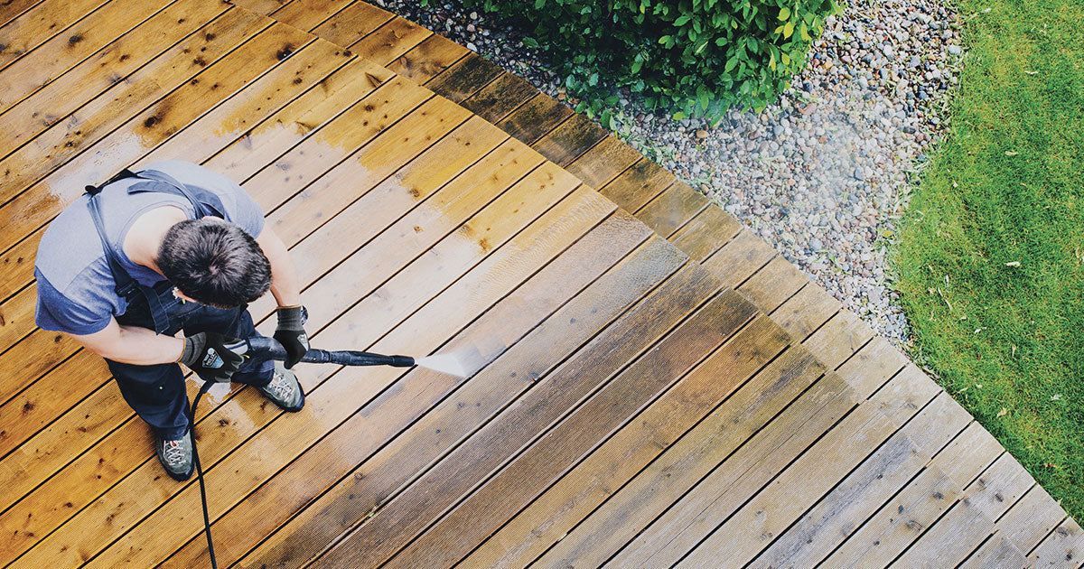 A man power washing a deck, wearing a pair of Helix 1091 safety gloves.
